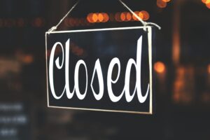 A close-up of a 'Closed' sign hanging against a blurred, bokeh background, creating a warm, inviting atmosphere.